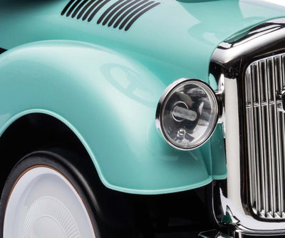 Hopeinen leikkiauto Rolls-Royce-mallina vihreällä mintunvärisellä pohjalla.