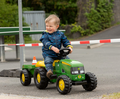 Punainen Rolly Toys -traktori John Deere -logolla ja keltainen perävaunu.
